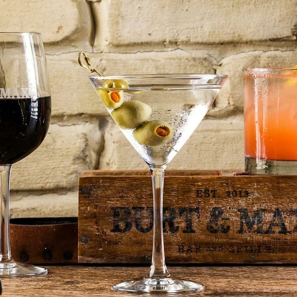 Red wine, martini, and two cocktails on a wooden table with a Burt & Max's crate.