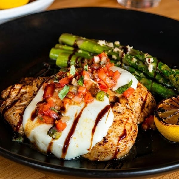 Grilled chicken topped with mozzarella, bruschetta, balsamic glaze, asparagus, and a charred lemon.