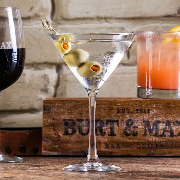 A red wine, martini, and two cocktails on a wooden table with a "Burt & Max's" crate.